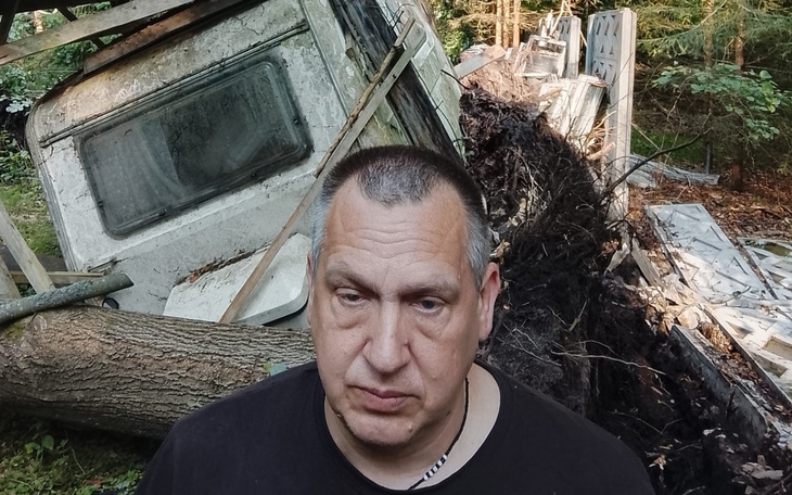 Mężczyzna z twarzową ekspresją przed szarą ścianą