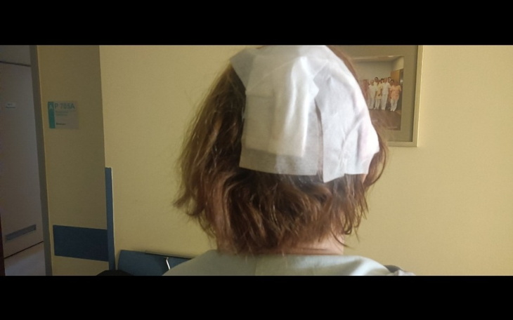 Kobieta z opatrunkiem na głowie, widok z tyłu.