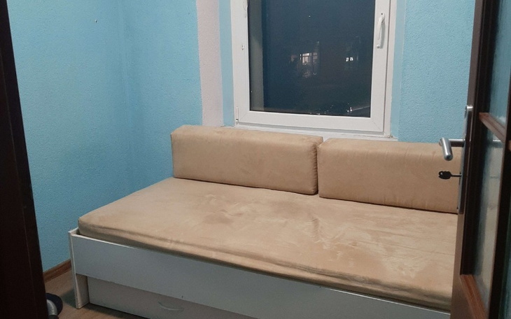 Pusty pokój z niebieskimi ścianami i kanapą przy oknie.