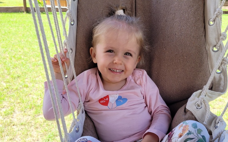 Mała dziewczynka na huśtawce, uśmiechnięta i szczęśliwa.