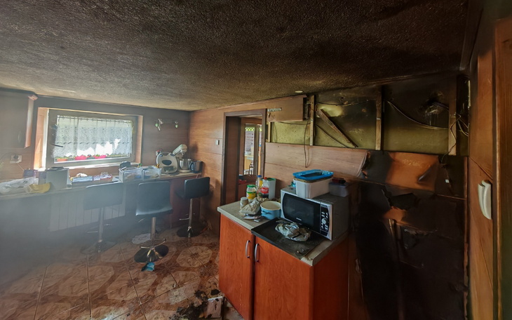 Zniszczona kuchnia po pożarze, z bałaganem i uszkodzeniami.