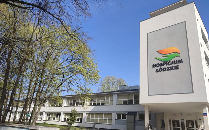 Budynek hospicjum z zielonym otoczeniem i niebieskim niebem.