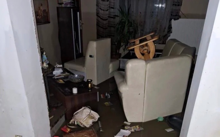 Zniszczone wnętrze mieszkania po powodzi, meble przewrócone.