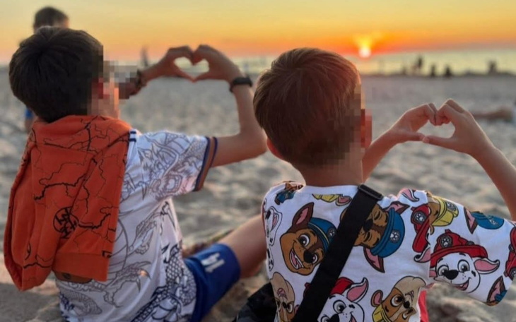 Dzieci na plaży tworzące serca rękami podczas zachodu słońca.
