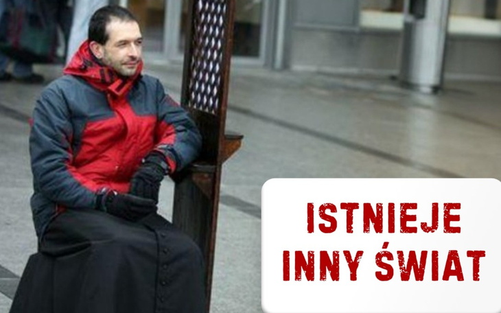 Mężczyzna w czerwonej kurtce siedzi na ławce z napisem 'Istnieje inny świat'.