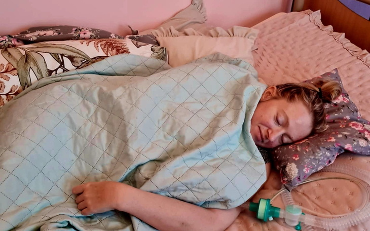 Kobieta śpiąca w łóżku, otulona kocem.