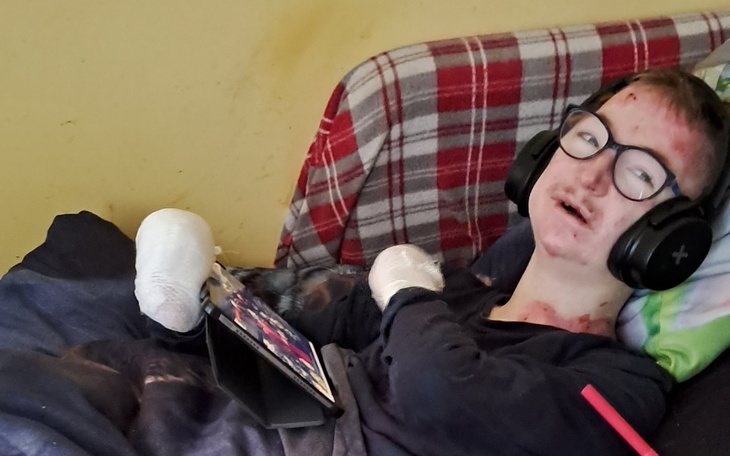 Chłopiec w słuchawkach, korzystający z tabletu, leżący na łóżku.