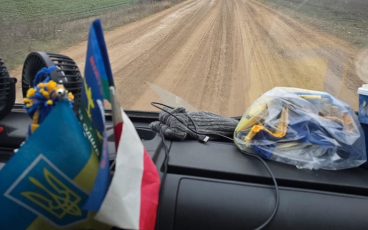 Widok z wnętrza samochodu na piaszczystą drogę.