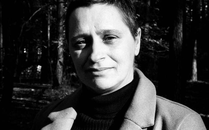 Kobieta w lesie, patrząca w obiektyw aparatu.