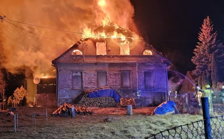 Dom w płomieniach, z akcją gaśniczą w nocy.