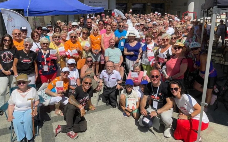 Duża grupa ludzi na wydarzeniu, wszyscy uśmiechnięci.