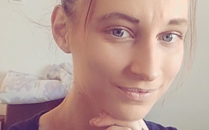 Portret kobiety z uśmiechem, w naturalnym otoczeniu.