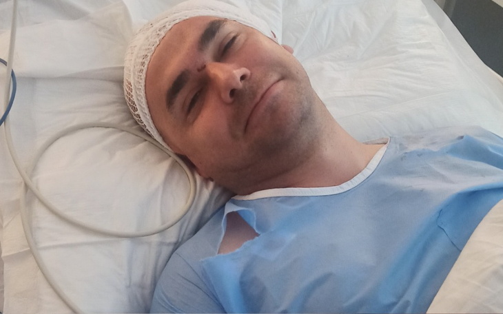 Mężczyzna w szpitalnym łóżku z uśmiechem na twarzy.