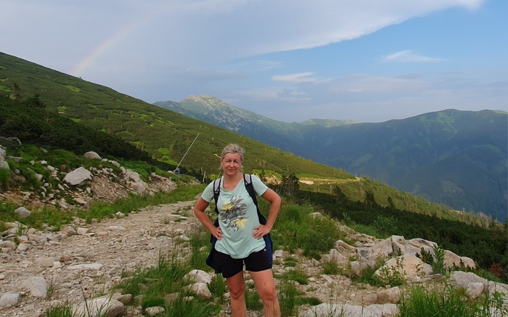 Kobieta na górskim szlaku z widokiem na dolinę.