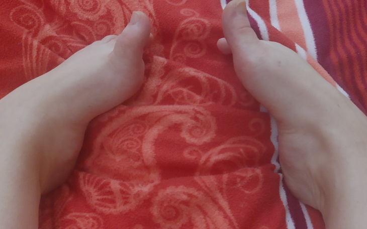 Dwie ręce trzymają się nawzajem na czerwonym kocu.