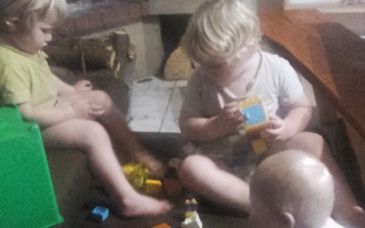 Dzieci bawiące się klockami na podłodze.