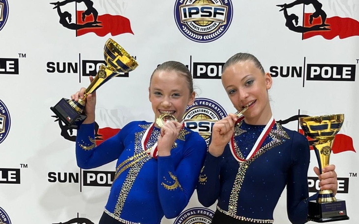 Dwie dziewczynki z medalami na zawodach sportowych.