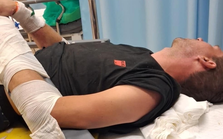 Mężczyzna w szpitalu, leżący z opatrunkiem na ręce.
