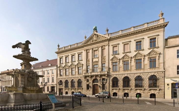 Zabytkowy budynek z fontanną na placu.