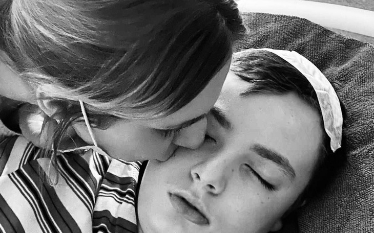 Kobieta całuje chłopca leżącego w szpitalu, wyraża troskę.