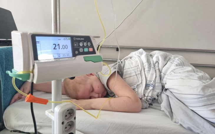 Dziecko śpiące w szpitalnym łóżku, z monitorującym urządzeniem obok.