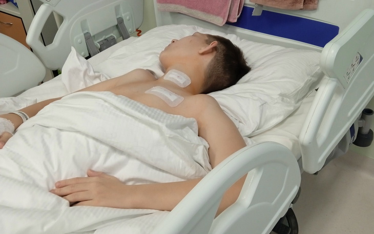 Chłopiec leży w szpitalnym łóżku po operacji.