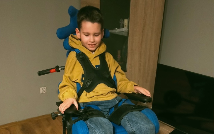 Chłopiec w specjalnym wózku, uśmiechający się.