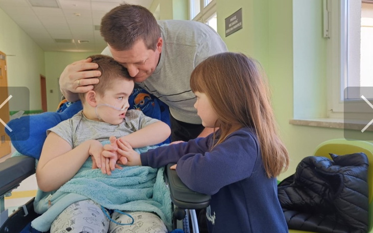 Chłopiec w wózku inwalidzkim z bliskimi w szpitalu.