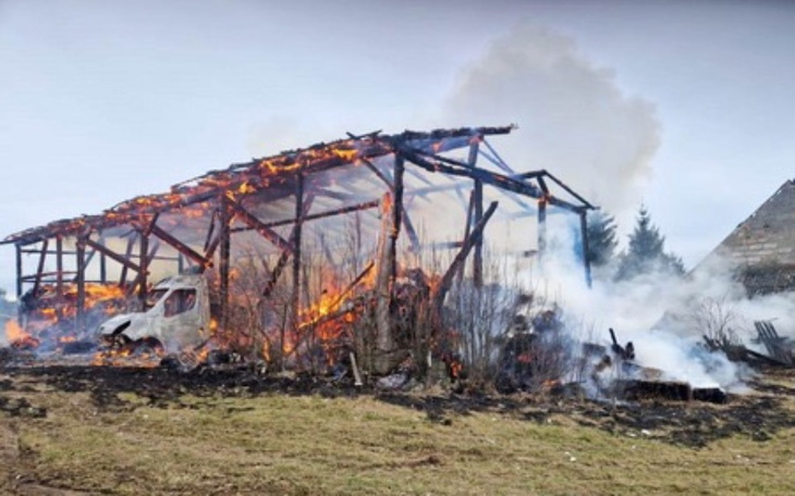Zniszczony budynek w ogniu, dym unoszący się w powietrzu.