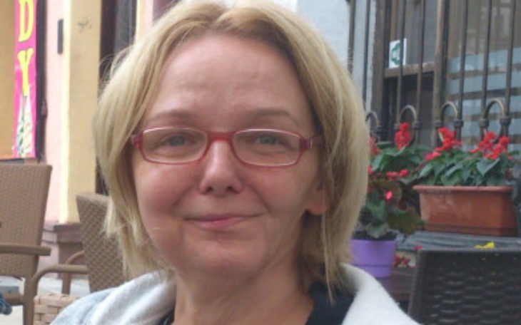 Kobieta z okularami uśmiechająca się w plenerze.