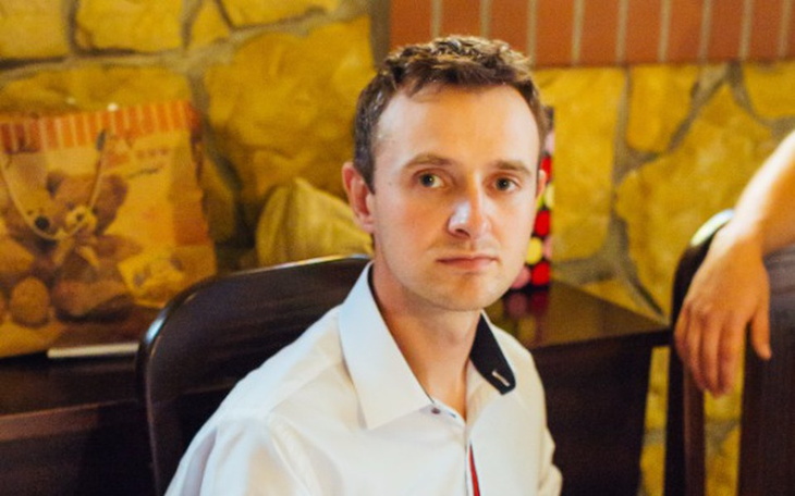 Mężczyzna w białej koszuli siedzący przy stole.