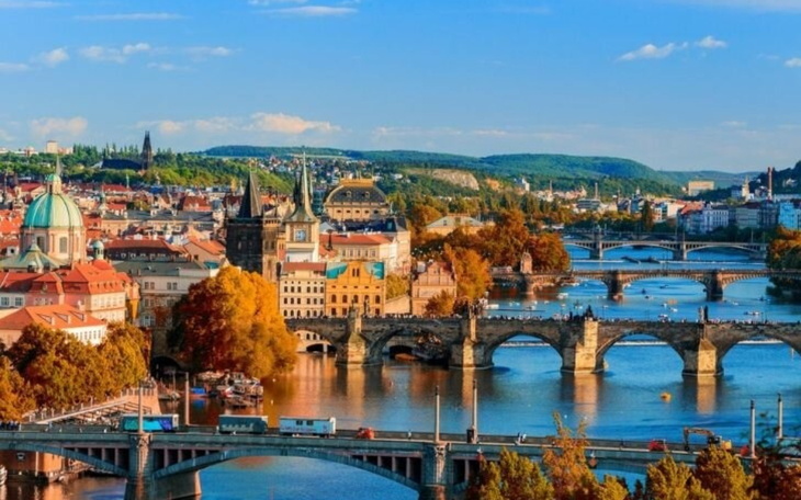 Panorama Pragi z mostami i kolorowymi budynkami w tle.