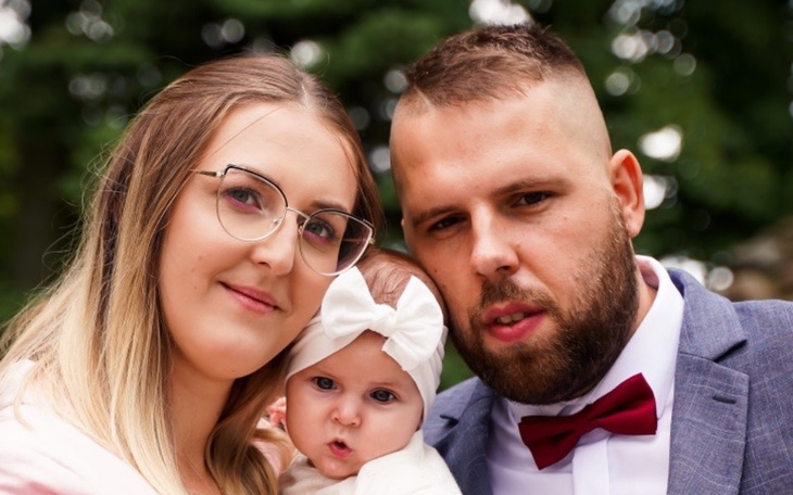 Rodzina pozująca z małym dzieckiem w eleganckich strojach.