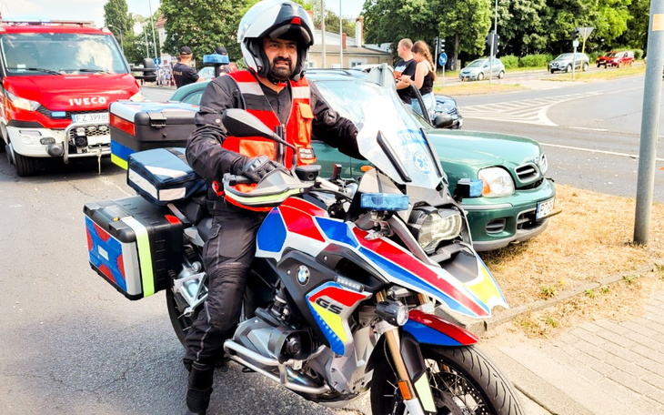 Mężczyzna na motocyklu ratunkowym, w tle ruch uliczny.