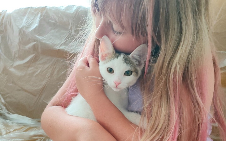 Dziewczynka przytulająca białego kota w radosnej chwili.