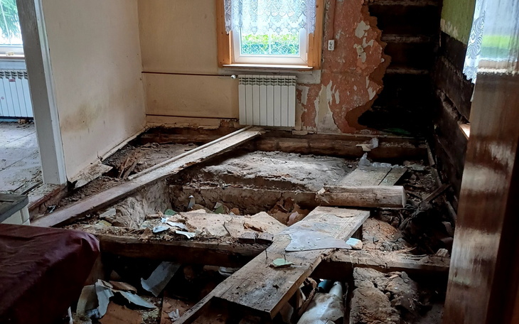 Zniszczone wnętrze domu z odsłoniętymi podłogami i uszkodzeniami ścian.