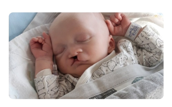 Noworodek śpiący w szpitalnym łóżeczku, z rurką tlenową.