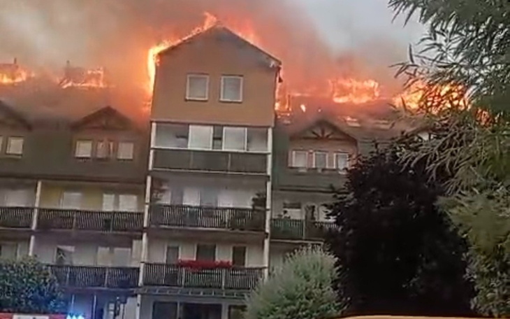 Pożar na dachu budynku, z płomieniami i dymem.