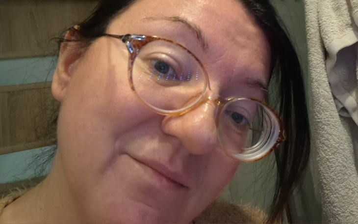 Kobieta w okularach, uśmiechająca się do kamery.