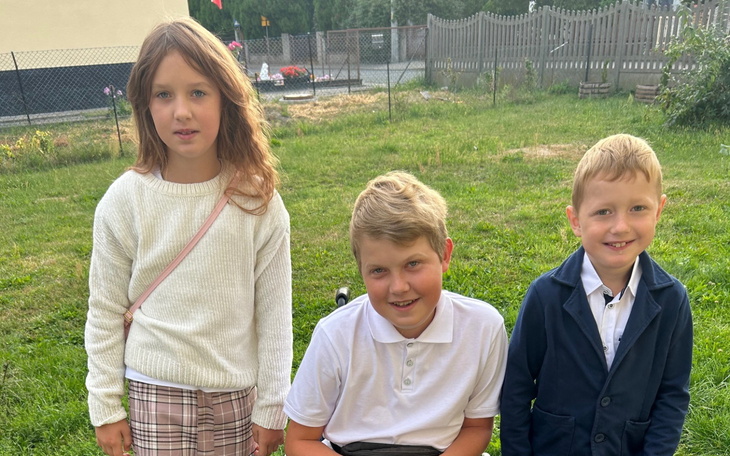 Grupa dzieci z darami, uśmiechnięta w sali.