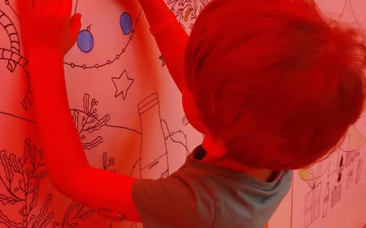 Dziecko rysuje na ścianie w kolorowym pomieszczeniu.