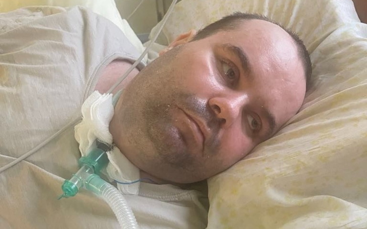 Mężczyzna leżący w szpitalnym łóżku, z rurką do oddychania.