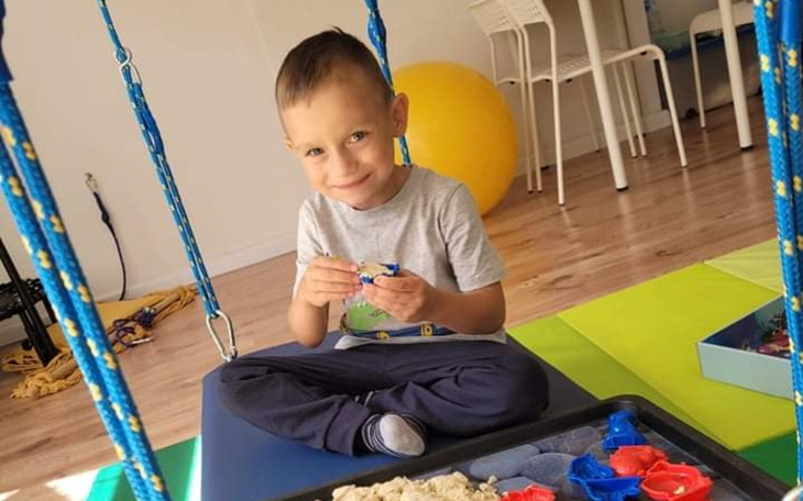 Uśmiechnięty chłopiec bawiący się w kolorowym pomieszczeniu.