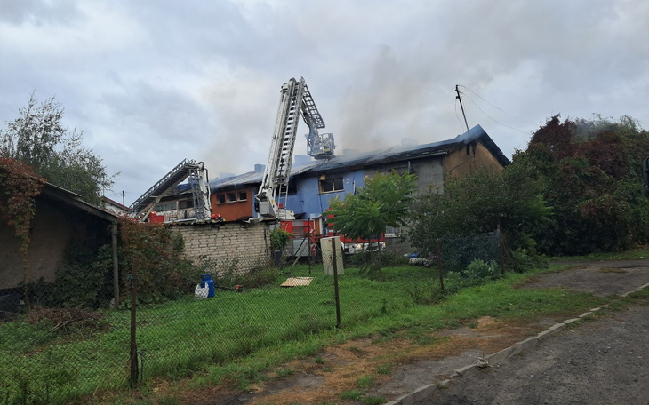 Pożar budynku z wozami strażackimi w akcji.