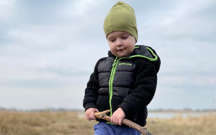 Mały chłopiec trzymający patyk na tle krajobrazu.