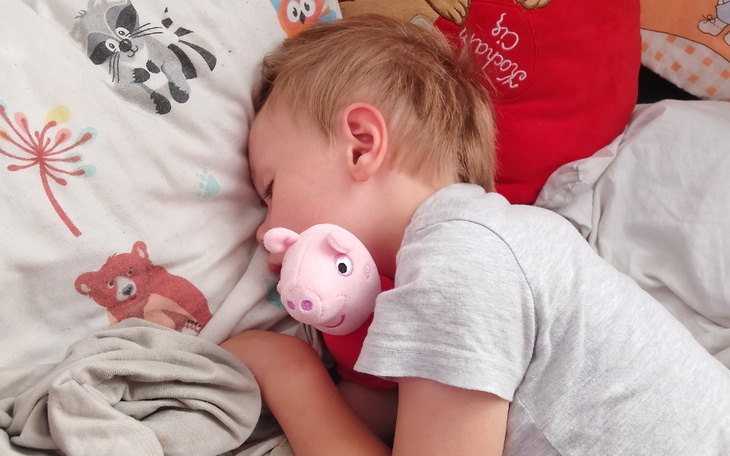 Mały chłopiec śpiący z pluszowym zwierzątkiem.