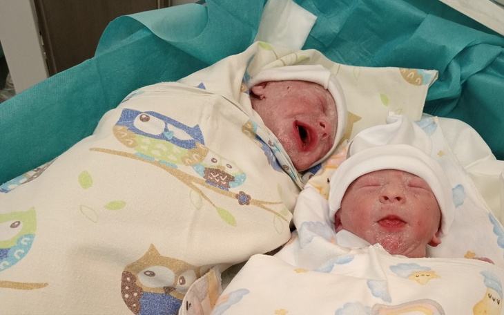 Noworodki owinięte w kocyki, z uśmiechami na twarzach.