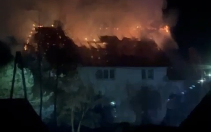 Płonący budynek w nocy, ogień wydobywa się z dachu.