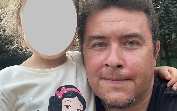 Mężczyzna z dzieckiem, oboje uśmiechnięci, w parku.