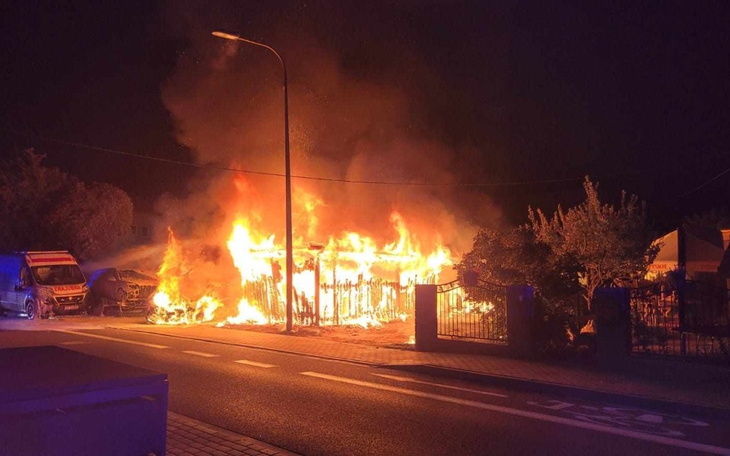 Płonący budynek w nocy, ogień i dym.